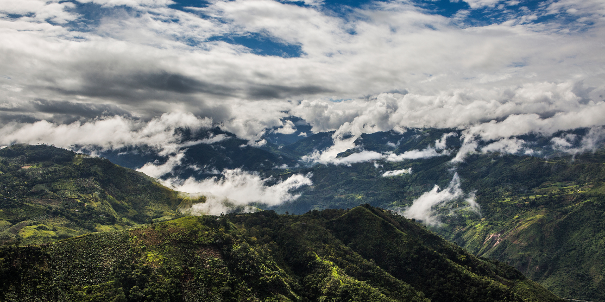 Headerbild für Kollektion Cacao-Schokoladenpulver Foto von grünen Bergen in Peru mit Wolken